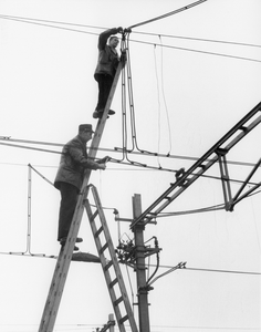 171699 Afbeelding van electriciens van het seinwezen van de N.S. tijdens werkzaamheden aan de bovenleiding te Maarssen.